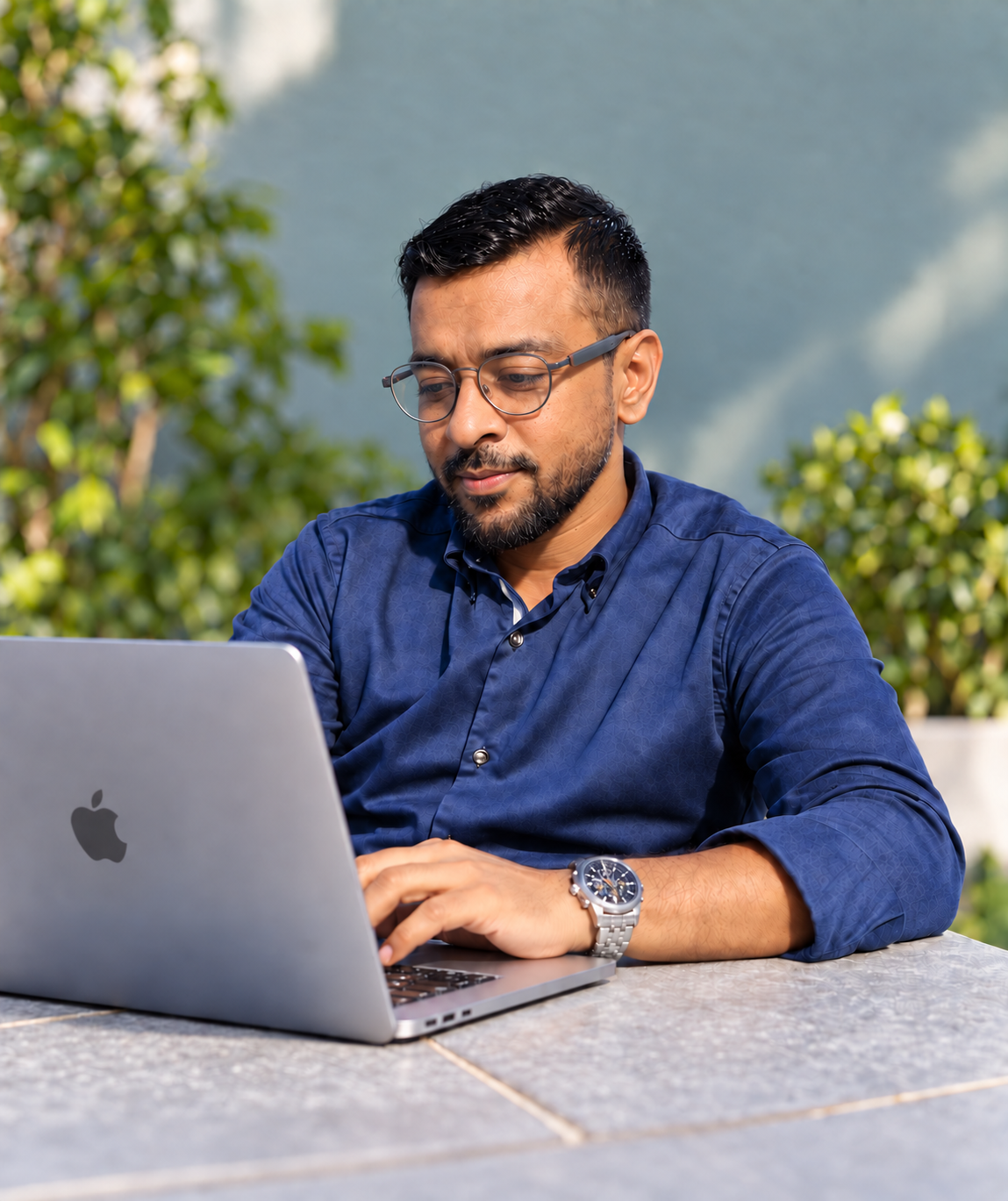 Kamrul Hasan working at his MacBook, wearing grey glasses